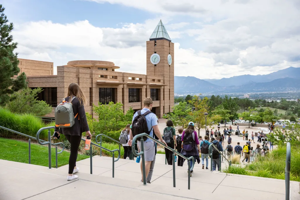 students walking on campus with El Pomar clocktower in the background