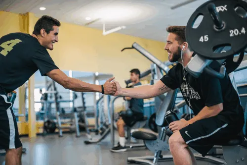 Two people shaking hands on a weight bench.