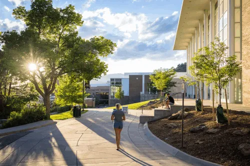 Student walking next to Dwire Hall in the sun