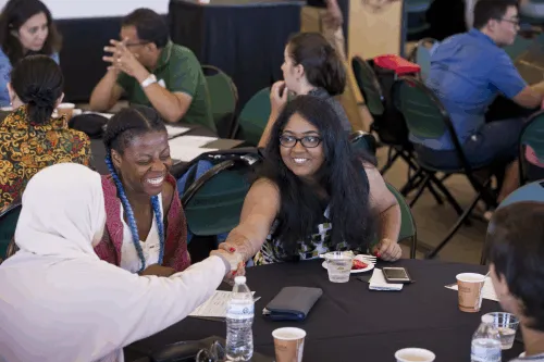 Students at table smiling.